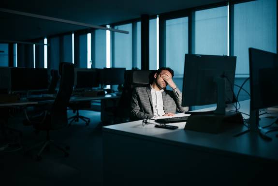 Mann sitzt erschöpft nachts im Office