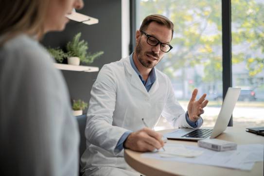 Männlicher Arzt, der einem Patienten in einem Büro ein Rezept schreibt
